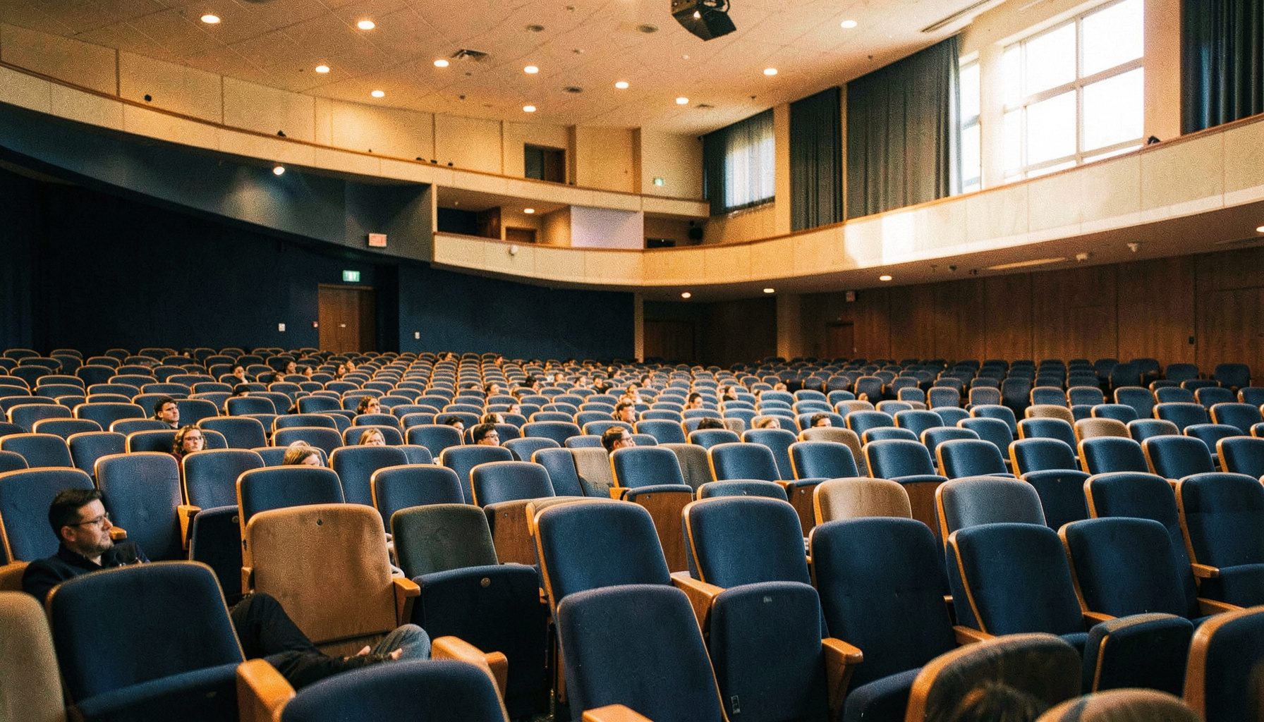 Auditorio universitario con asientos ordenados y luz suave, tonos azul marino y beige